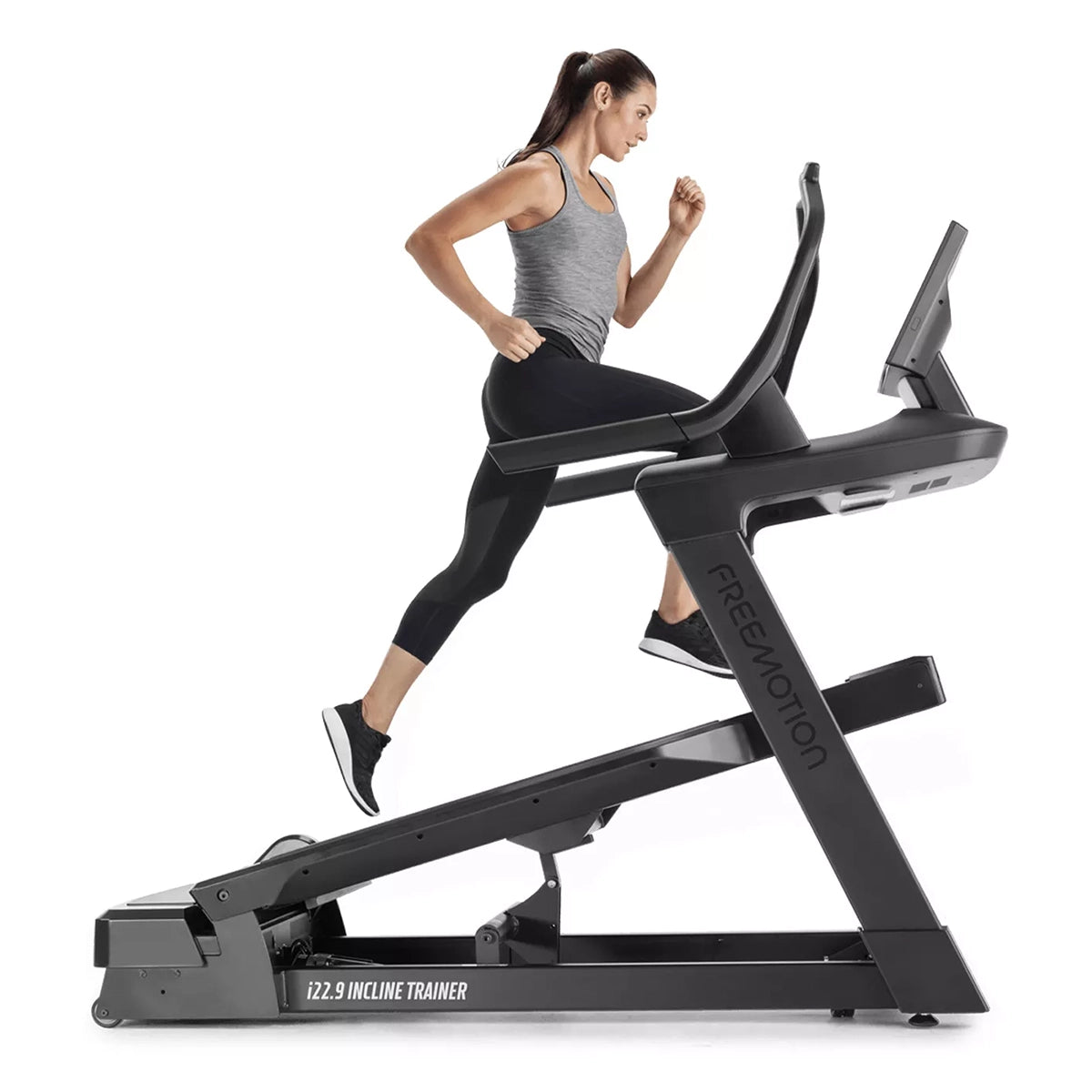 Freemotion i22.9 Incline treadmill Trainer in black and inclined, with person running on it, with a side on view