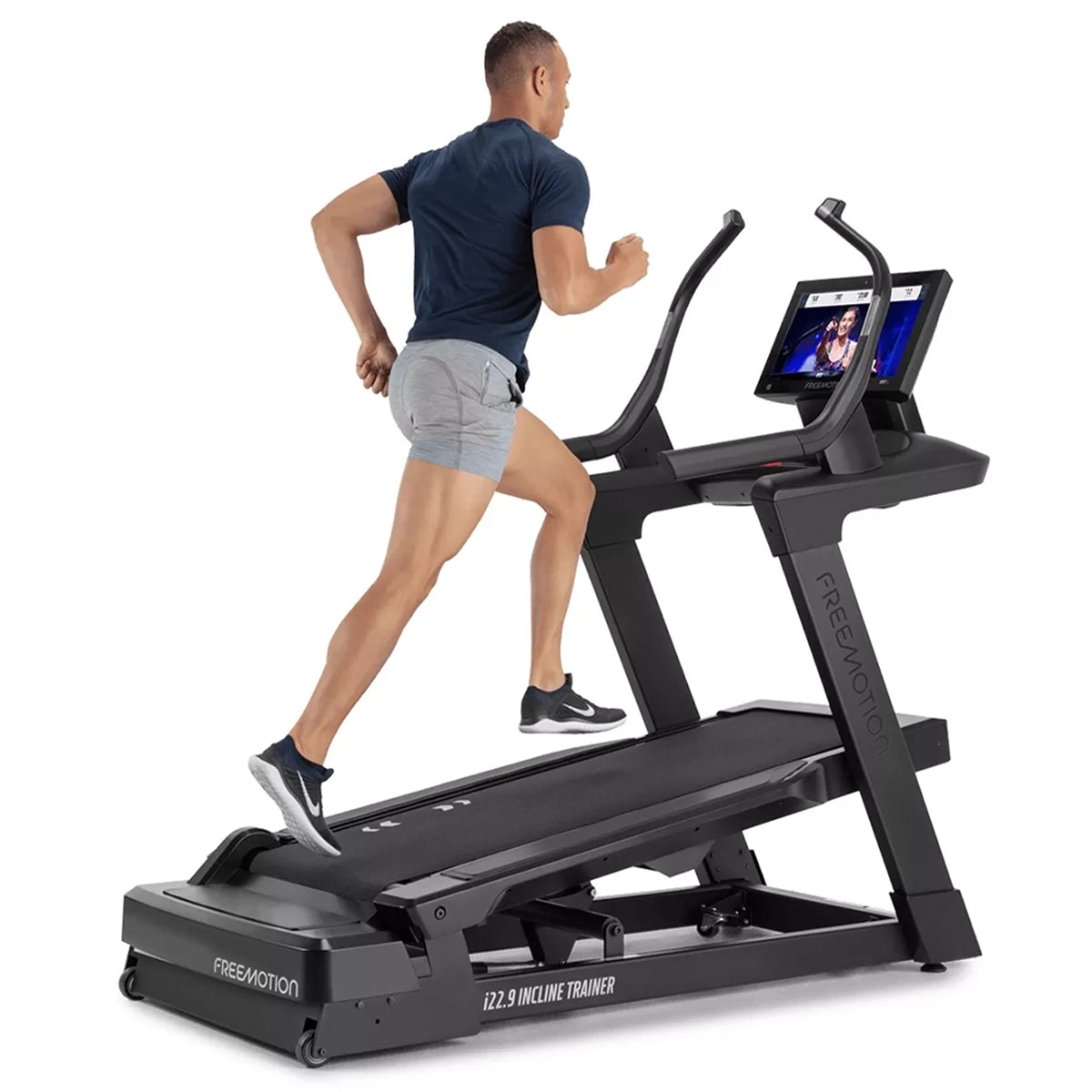 Freemotion i22.9 Incline treadmill Trainer in black and inclined, with a person running, from a diagonal view 